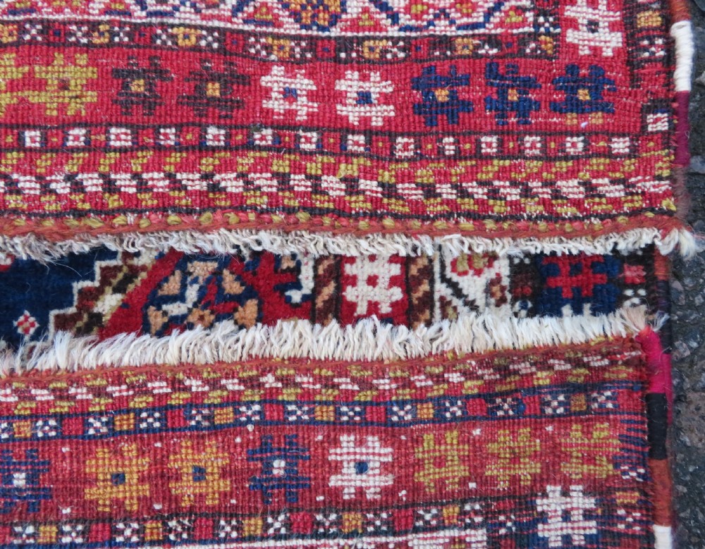 An antique hand-knotted Qashqai wool rug featuring a central ivory diamond medallion surrounded by detailed geometric and animal motifs on a navy blue field with a red border. View XIV