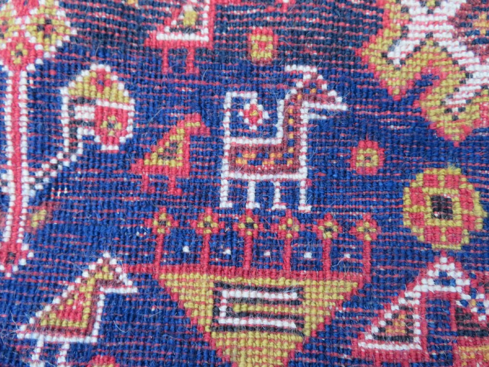An antique hand-knotted Qashqai wool rug featuring a central ivory diamond medallion surrounded by detailed geometric and animal motifs on a navy blue field with a red border. View XV