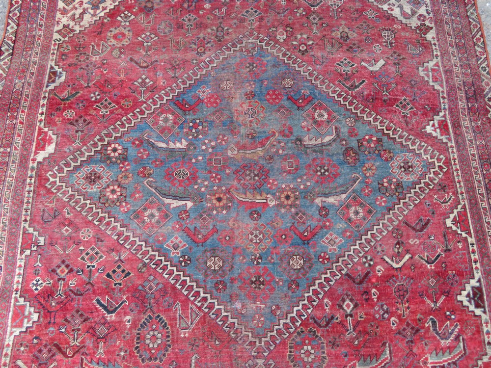 A long hand-knotted antique Persian Khamseh carpet featuring geometric diamond medallions and intricate tribal motifs in red, blue, and cream tones. View IV
