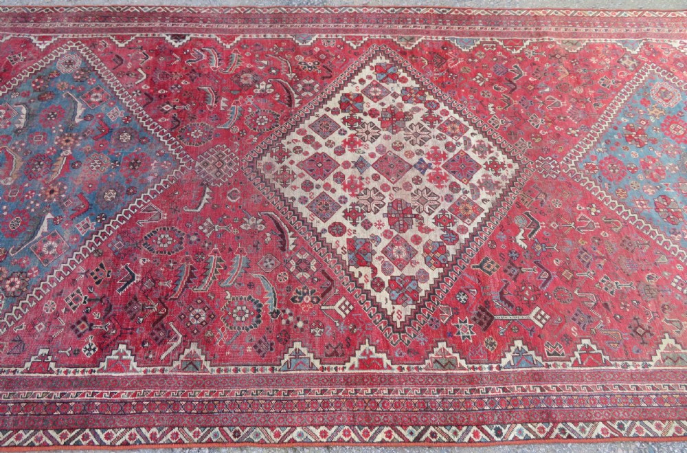 A long hand-knotted antique Persian Khamseh carpet featuring geometric diamond medallions and intricate tribal motifs in red, blue, and cream tones. View VIII