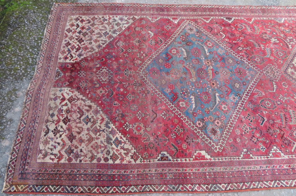 A long hand-knotted antique Persian Khamseh carpet featuring geometric diamond medallions and intricate tribal motifs in red, blue, and cream tones. View IX