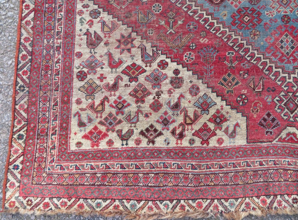 A long hand-knotted antique Persian Khamseh carpet featuring geometric diamond medallions and intricate tribal motifs in red, blue, and cream tones. View X
