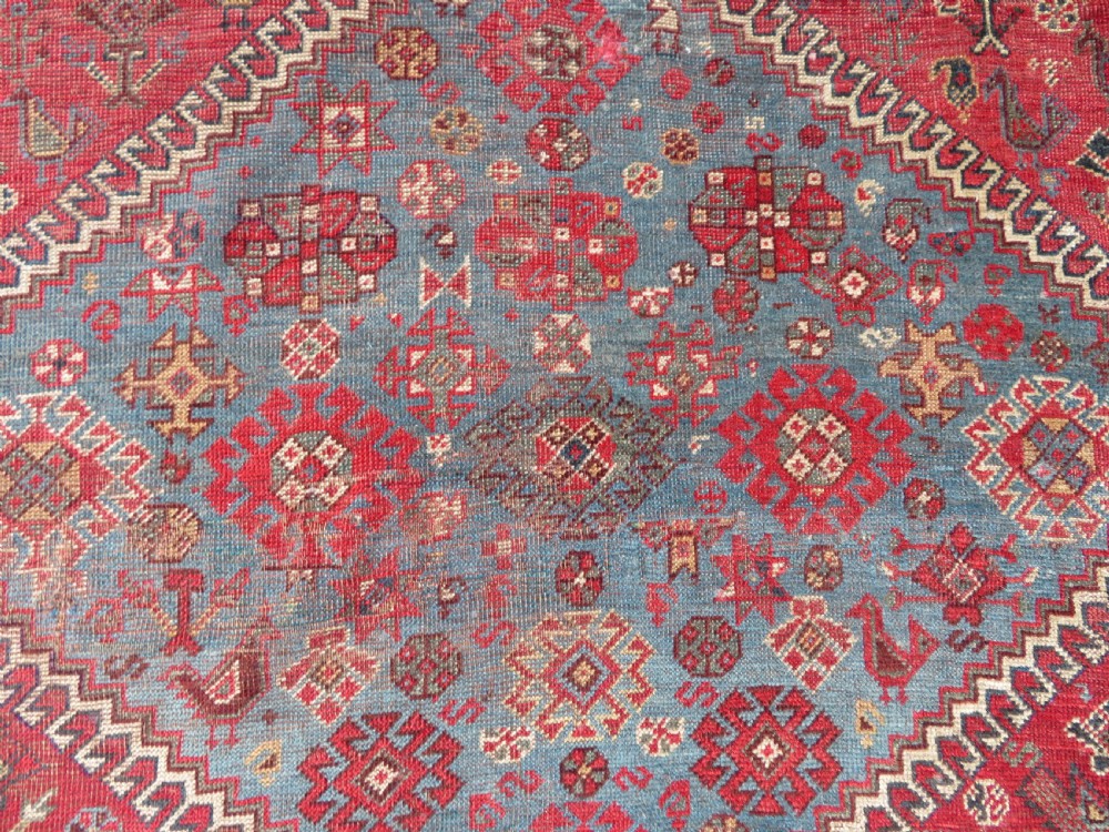 A long hand-knotted antique Persian Khamseh carpet featuring geometric diamond medallions and intricate tribal motifs in red, blue, and cream tones. View XIV