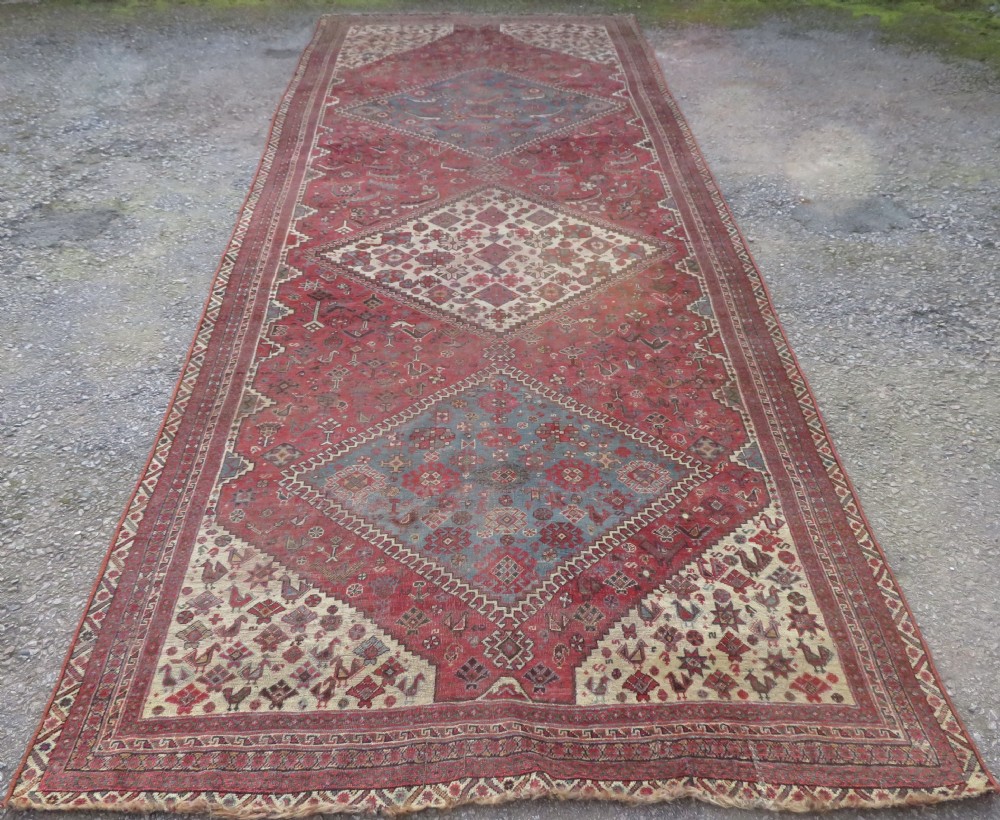 A long hand-knotted antique Persian Khamseh carpet featuring geometric diamond medallions and intricate tribal motifs in red, blue, and cream tones. View II