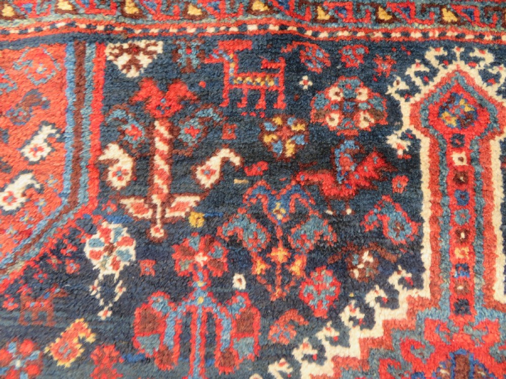 An antique Persian Qashqai hand-knotted wool rug with a dark navy blue field, double red geometric medallion, and multi-band patterned borders. View V