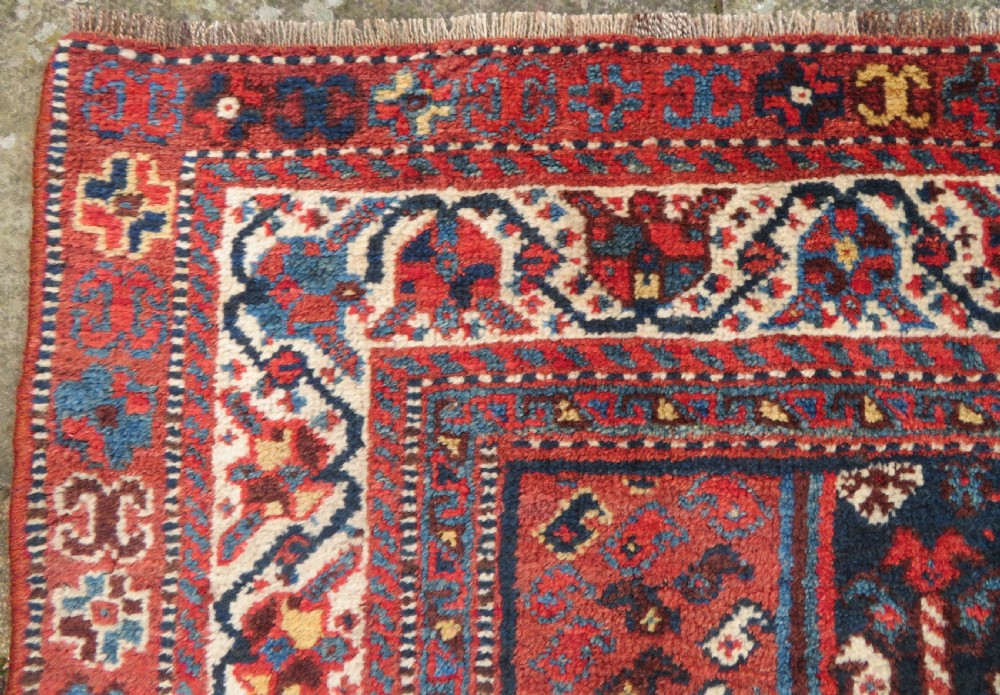 An antique Persian Qashqai hand-knotted wool rug with a dark navy blue field, double red geometric medallion, and multi-band patterned borders. View VII