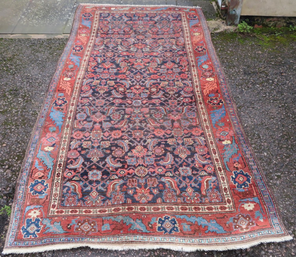 An antique Persian Bidjar Kelleh wool long rug featuring a central navy blue geometric botanical field surrounded by terracotta and blue borders.