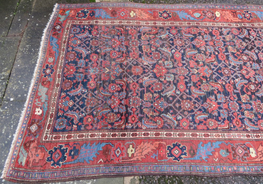 An antique Persian Bidjar Kelleh wool long rug featuring a central navy blue geometric botanical field surrounded by terracotta and blue borders. View III
