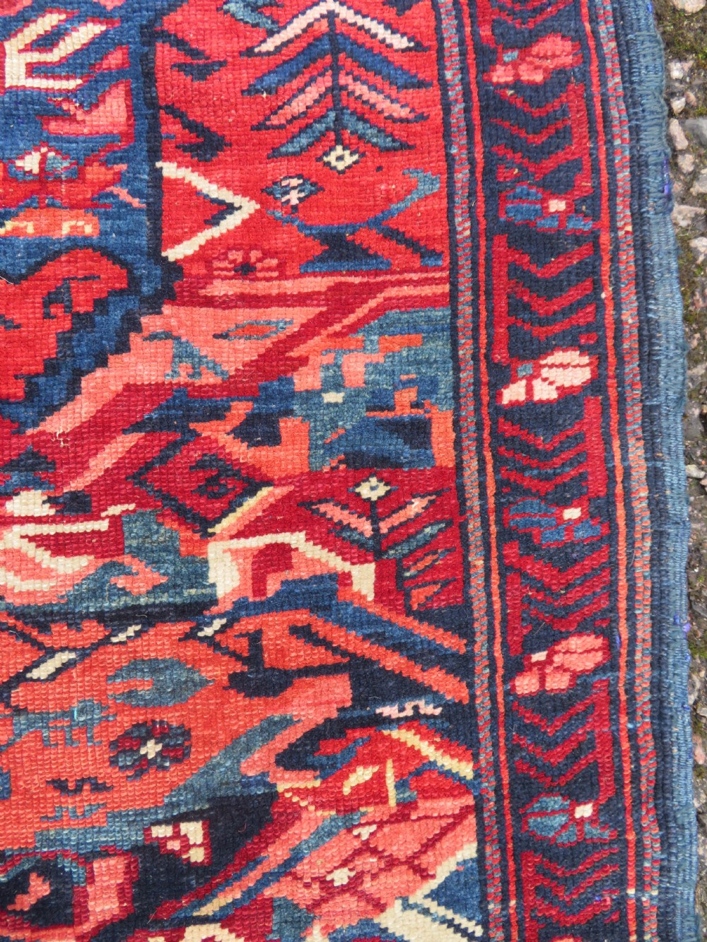 A rectangular hand-knotted antique Caucasian Kuba rug featuring complex geometric motifs in deep red, navy blue, light blue, and cream. View VI