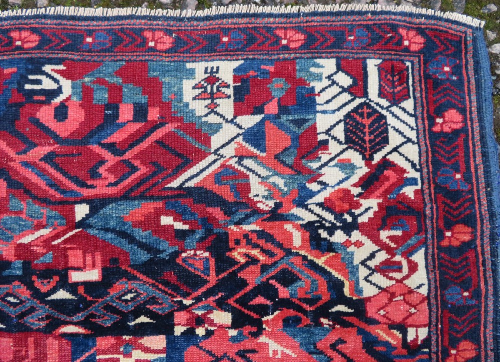 A rectangular hand-knotted antique Caucasian Kuba rug featuring complex geometric motifs in deep red, navy blue, light blue, and cream. View VII