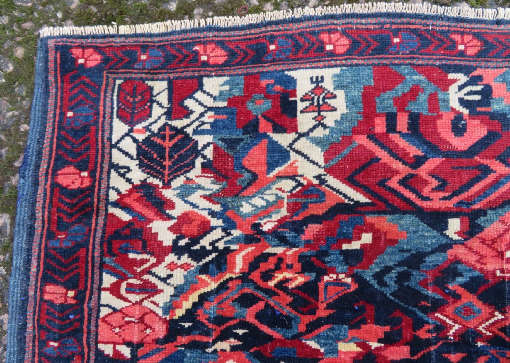 A rectangular hand-knotted antique Caucasian Kuba rug featuring complex geometric motifs in deep red, navy blue, light blue, and cream. View VIII