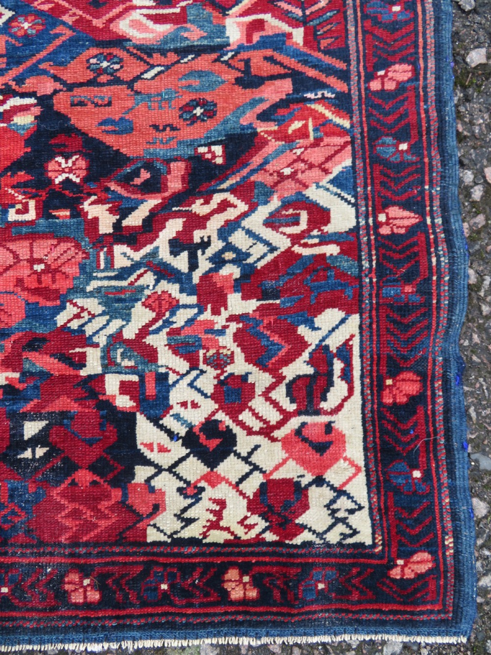 A rectangular hand-knotted antique Caucasian Kuba rug featuring complex geometric motifs in deep red, navy blue, light blue, and cream. View X