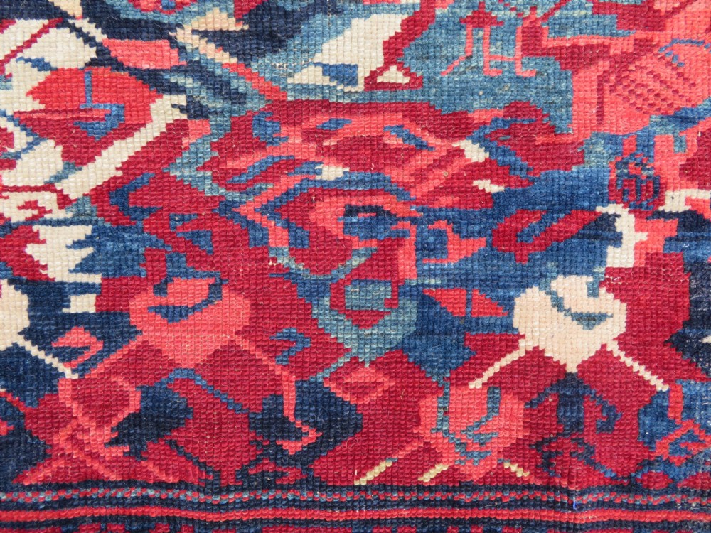 A rectangular hand-knotted antique Caucasian Kuba rug featuring complex geometric motifs in deep red, navy blue, light blue, and cream. View XI
