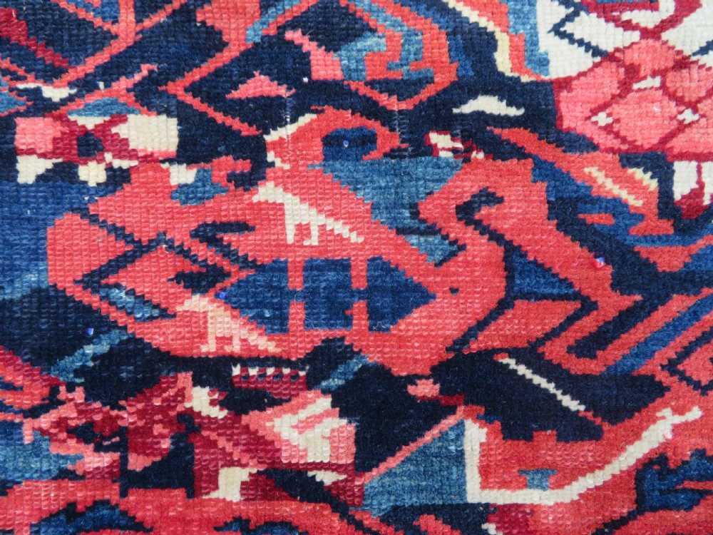 A rectangular hand-knotted antique Caucasian Kuba rug featuring complex geometric motifs in deep red, navy blue, light blue, and cream. View XII