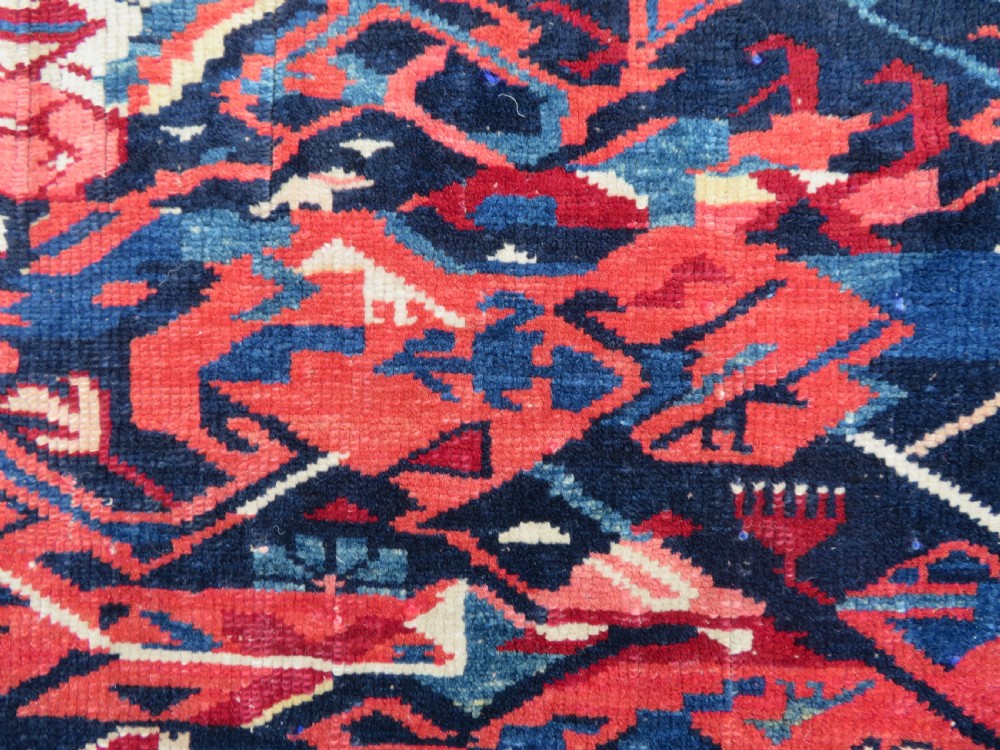 A rectangular hand-knotted antique Caucasian Kuba rug featuring complex geometric motifs in deep red, navy blue, light blue, and cream. View XIII