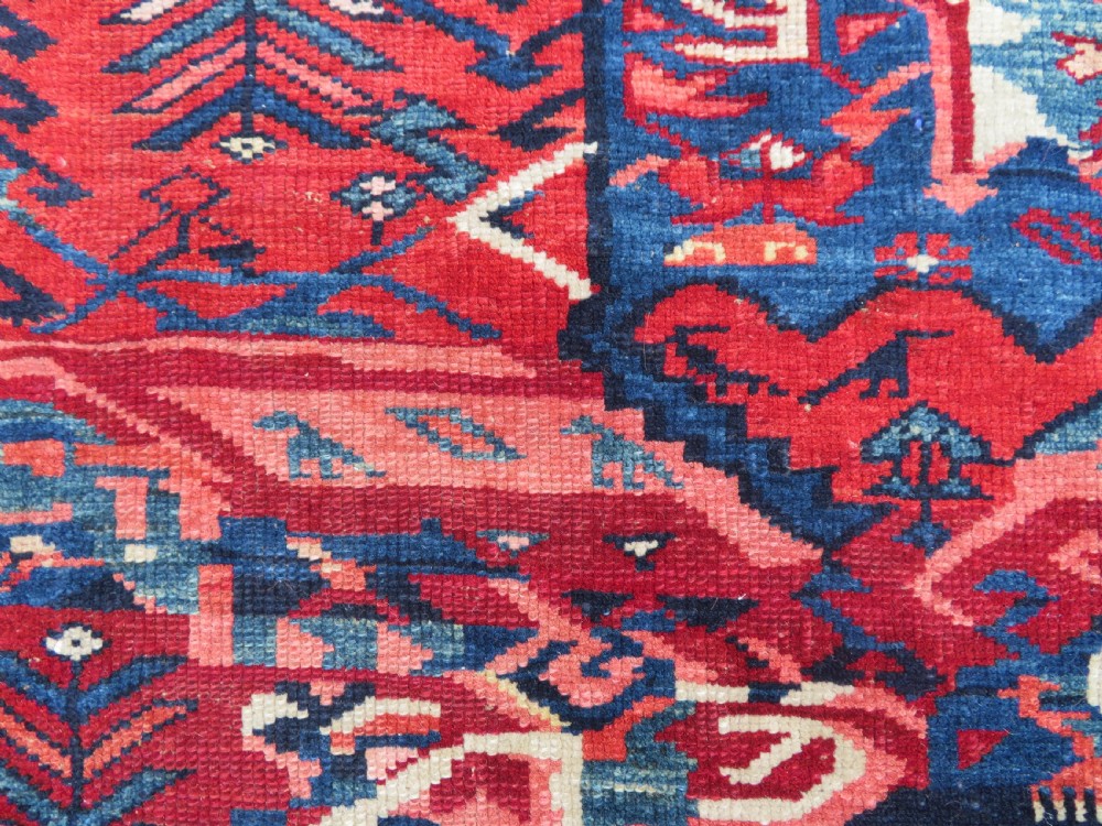 A rectangular hand-knotted antique Caucasian Kuba rug featuring complex geometric motifs in deep red, navy blue, light blue, and cream. View XIV