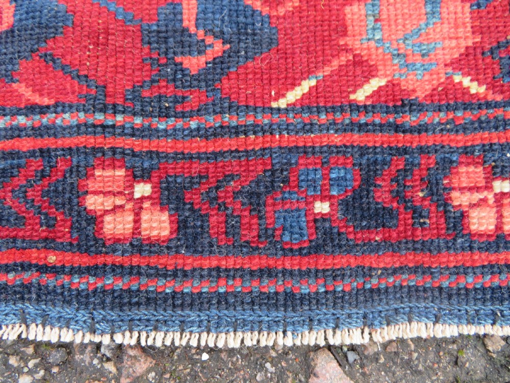 A rectangular hand-knotted antique Caucasian Kuba rug featuring complex geometric motifs in deep red, navy blue, light blue, and cream. View XVI