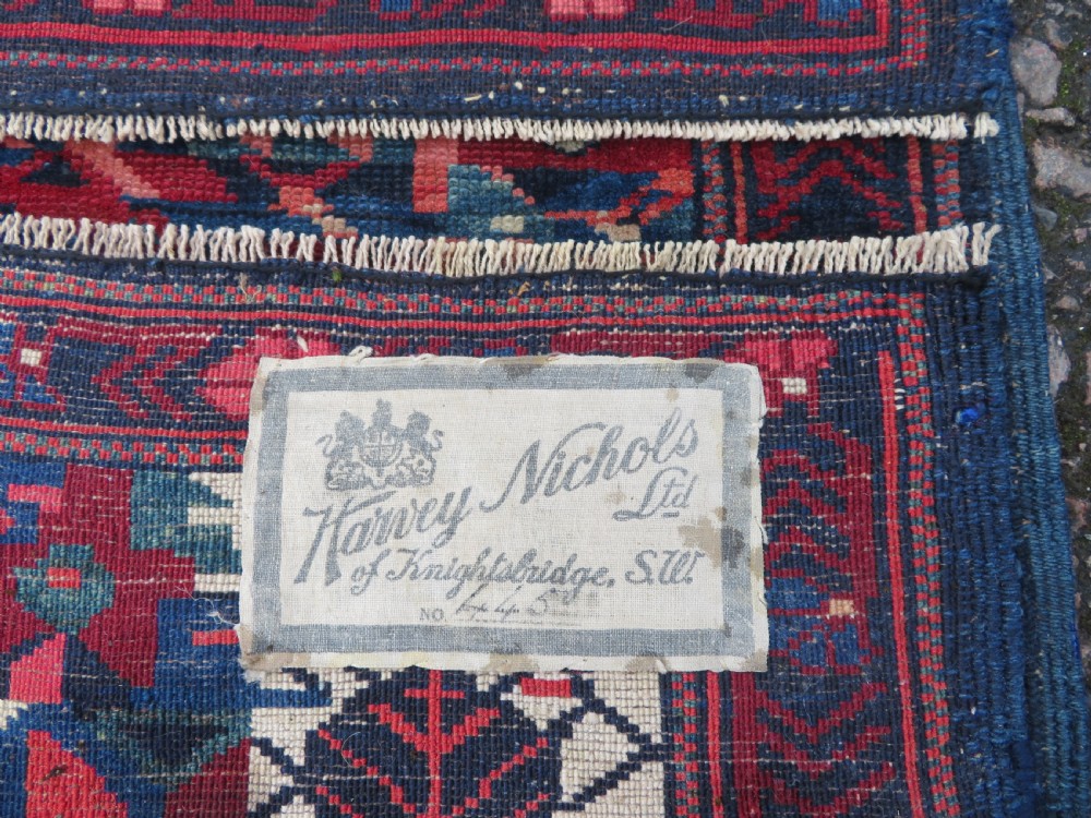A rectangular hand-knotted antique Caucasian Kuba rug featuring complex geometric motifs in deep red, navy blue, light blue, and cream. View XVIII