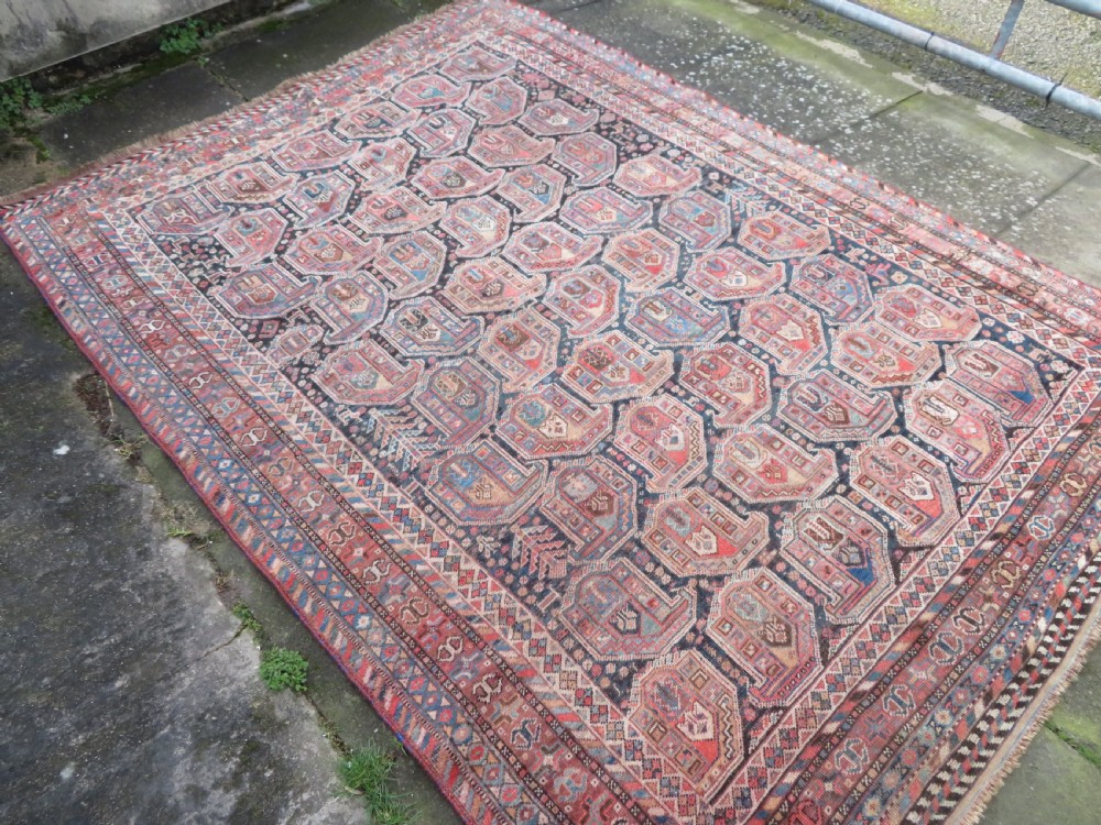 An antique Khamseh hand-knotted wool carpet featuring repeating stylised boteh motifs on a dark navy field with multi-banded geometric borders. View III