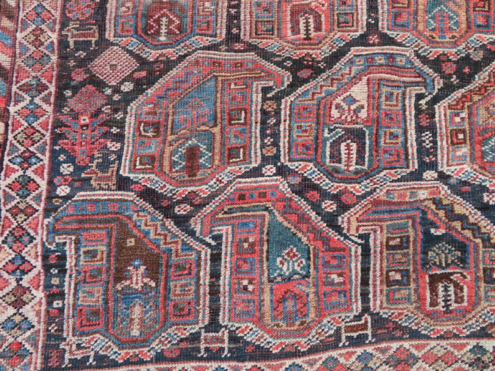 An antique Khamseh hand-knotted wool carpet featuring repeating stylised boteh motifs on a dark navy field with multi-banded geometric borders. View IV