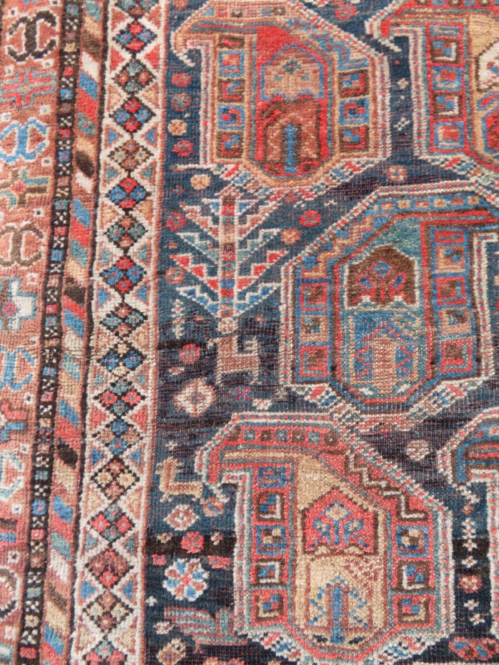 An antique Khamseh hand-knotted wool carpet featuring repeating stylised boteh motifs on a dark navy field with multi-banded geometric borders. View VI