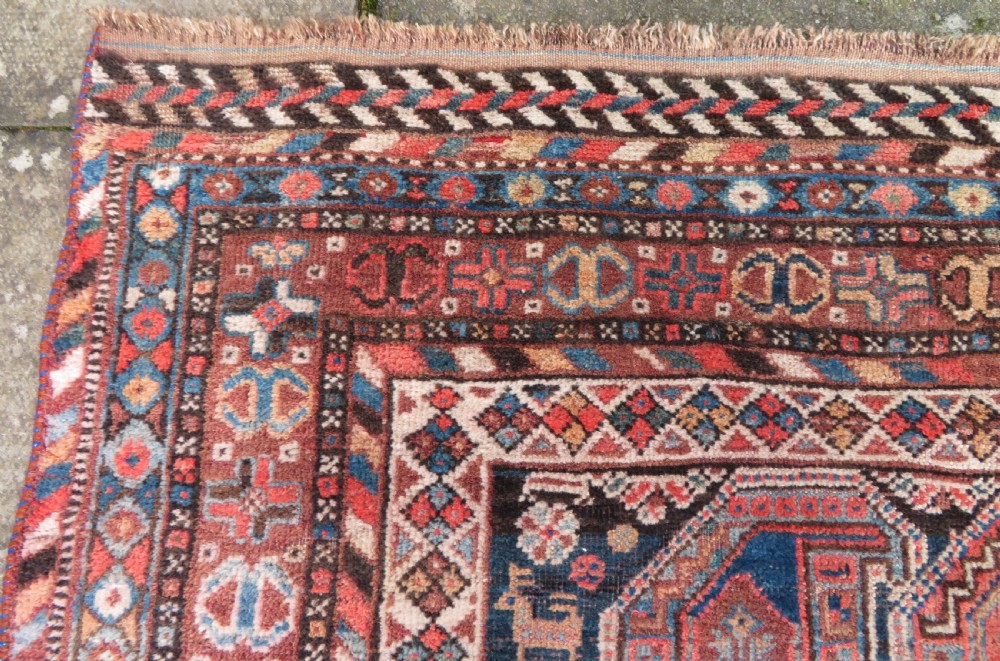 An antique Khamseh hand-knotted wool carpet featuring repeating stylised boteh motifs on a dark navy field with multi-banded geometric borders. View VIII
