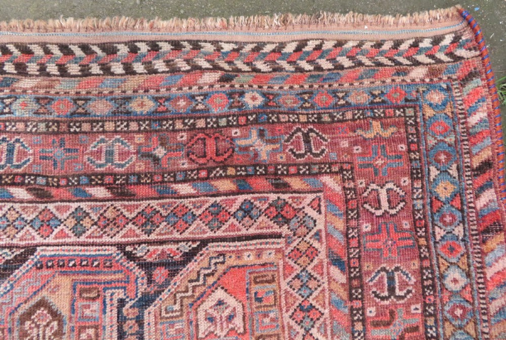 An antique Khamseh hand-knotted wool carpet featuring repeating stylised boteh motifs on a dark navy field with multi-banded geometric borders. View IX