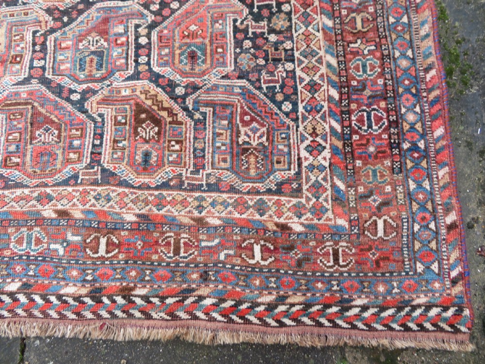 An antique Khamseh hand-knotted wool carpet featuring repeating stylised boteh motifs on a dark navy field with multi-banded geometric borders. View XI
