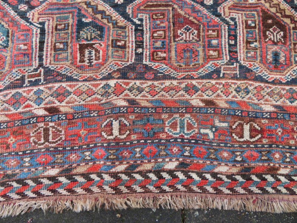 An antique Khamseh hand-knotted wool carpet featuring repeating stylised boteh motifs on a dark navy field with multi-banded geometric borders. View XII