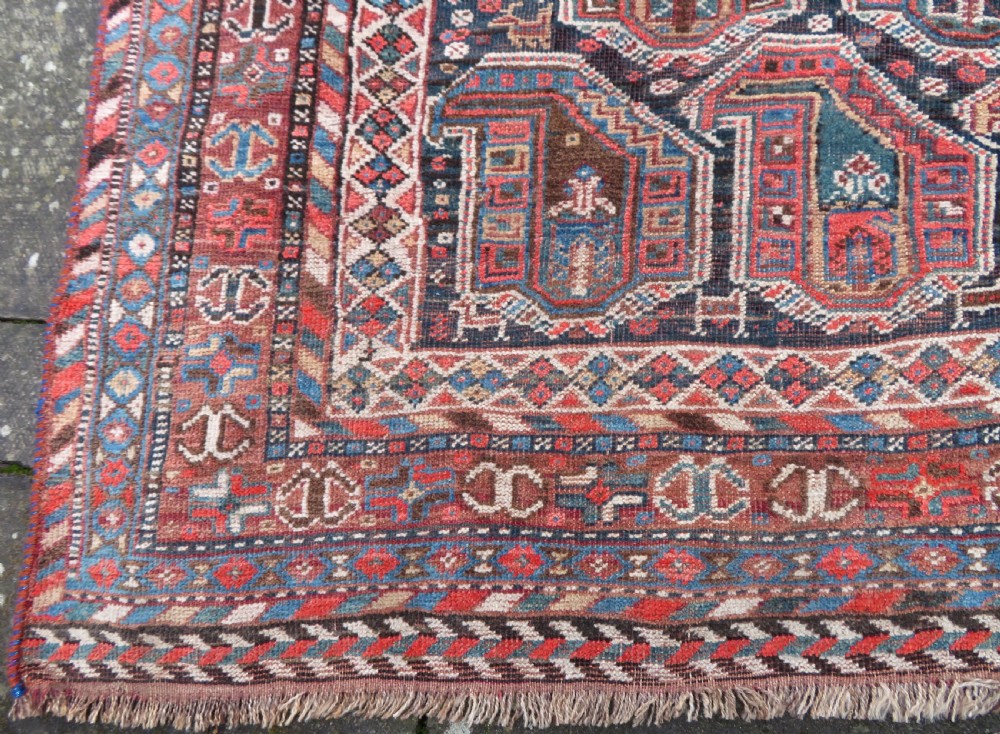 An antique Khamseh hand-knotted wool carpet featuring repeating stylised boteh motifs on a dark navy field with multi-banded geometric borders. View XIII