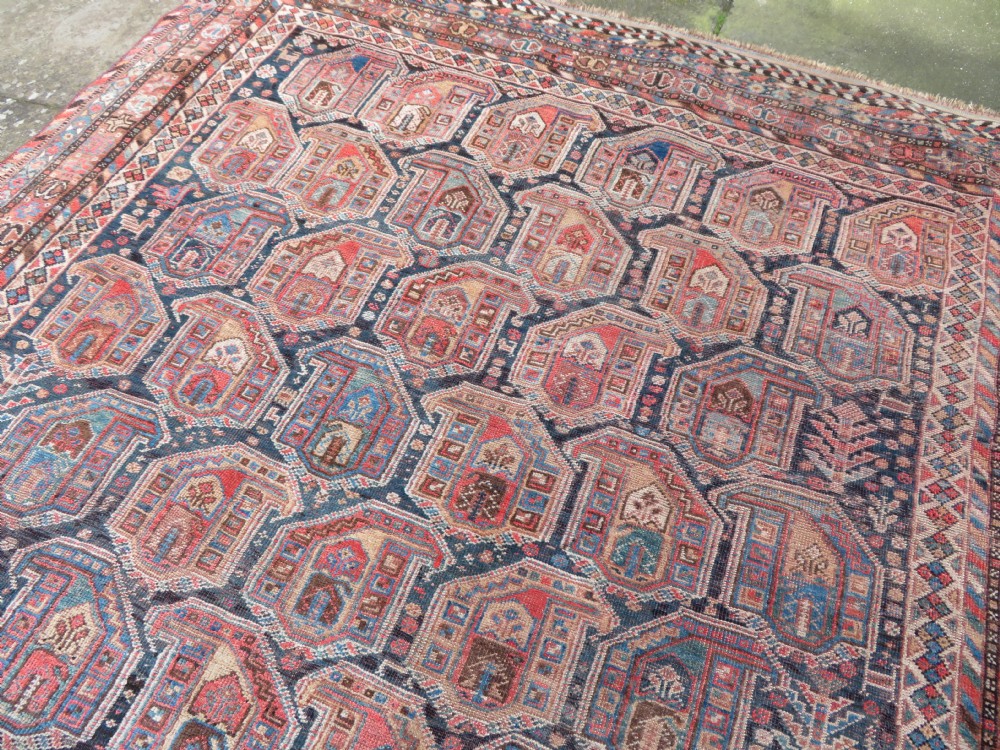 An antique Khamseh hand-knotted wool carpet featuring repeating stylised boteh motifs on a dark navy field with multi-banded geometric borders. View XVII
