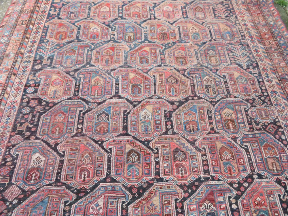 An antique Khamseh hand-knotted wool carpet featuring repeating stylised boteh motifs on a dark navy field with multi-banded geometric borders. View XVIII