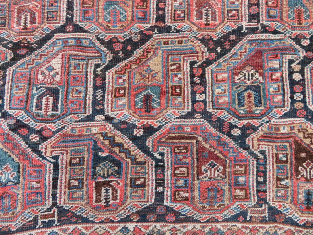 An antique Khamseh hand-knotted wool carpet featuring repeating stylised boteh motifs on a dark navy field with multi-banded geometric borders. View XIX