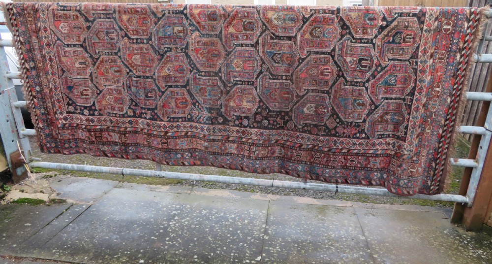 An antique Khamseh hand-knotted wool carpet featuring repeating stylised boteh motifs on a dark navy field with multi-banded geometric borders. View XXVIII