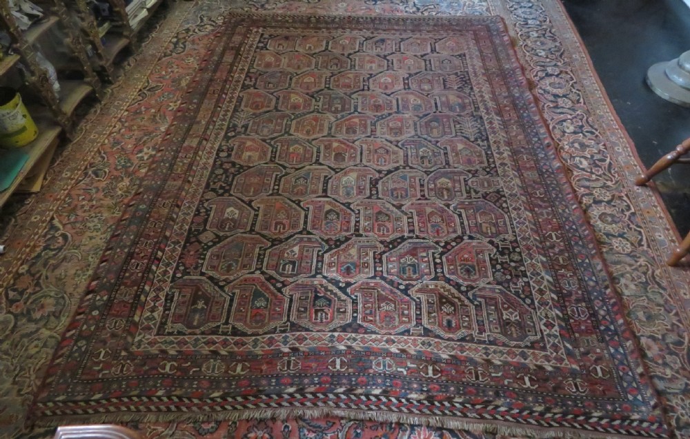An antique Khamseh hand-knotted wool carpet featuring repeating stylised boteh motifs on a dark navy field with multi-banded geometric borders. View XXX
