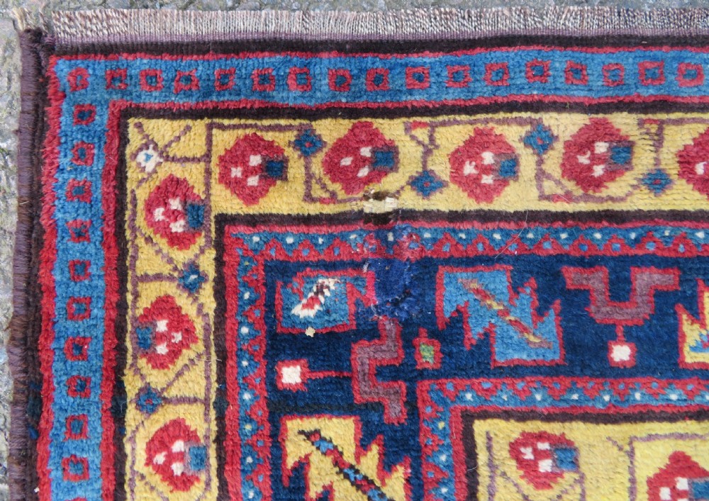 An antique hand-knotted Kurdish Kelleh long rug featuring a navy blue central field filled with repeating geometric motifs within multi-coloured yellow and red borders. View VII