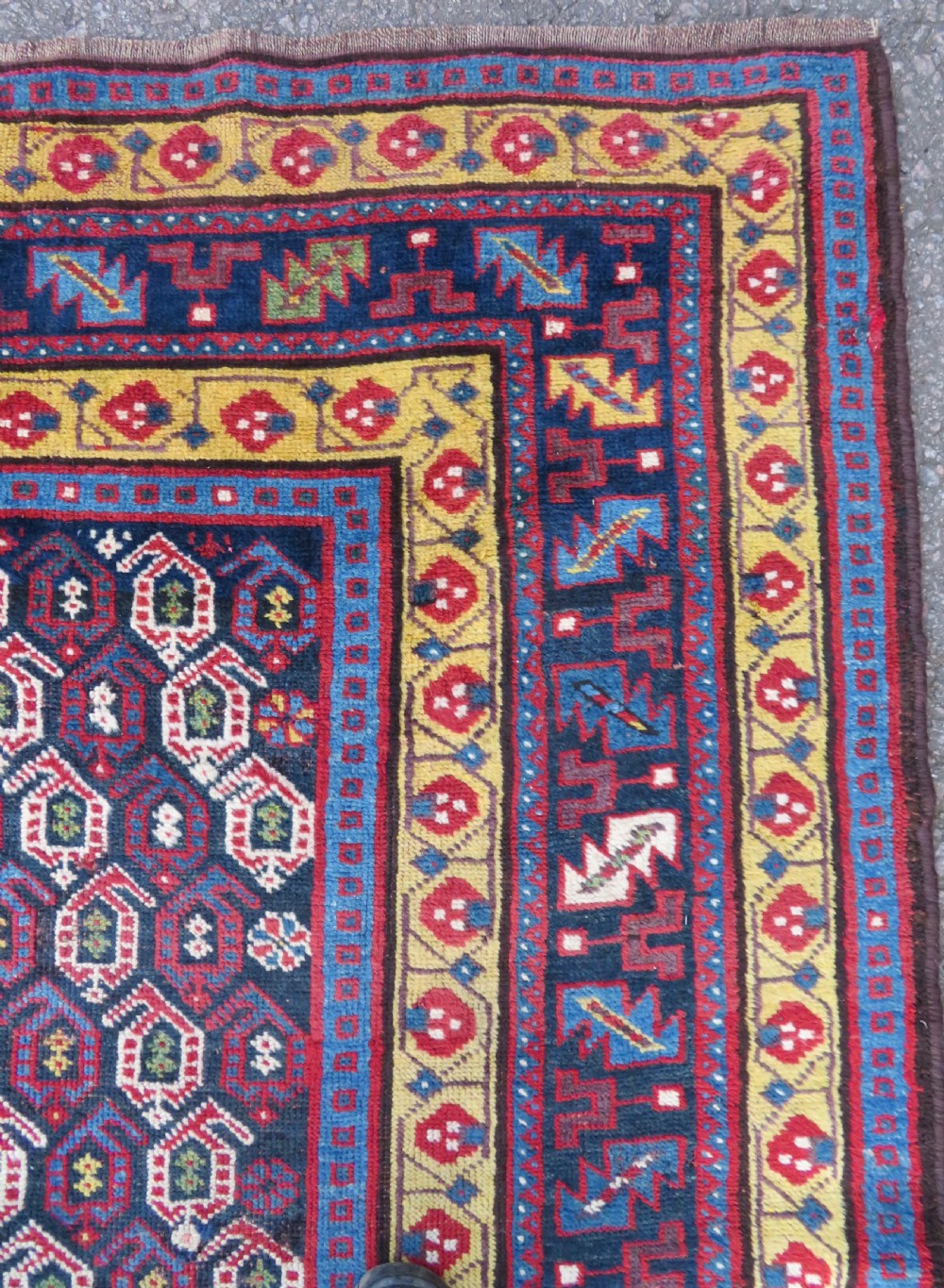 An antique hand-knotted Kurdish Kelleh long rug featuring a navy blue central field filled with repeating geometric motifs within multi-coloured yellow and red borders. View IX