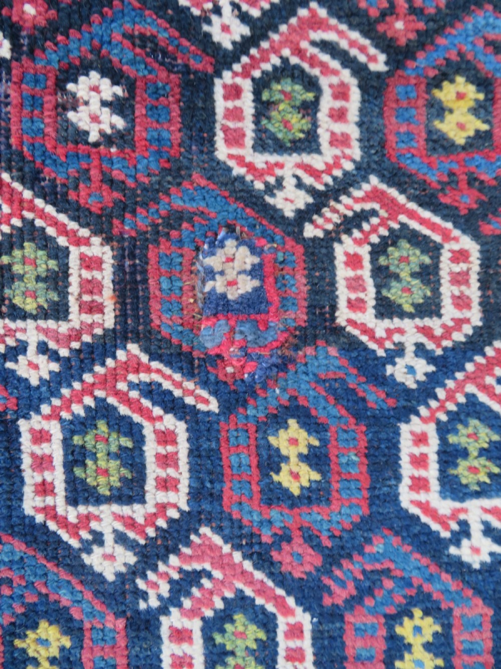 An antique hand-knotted Kurdish Kelleh long rug featuring a navy blue central field filled with repeating geometric motifs within multi-coloured yellow and red borders. View XI