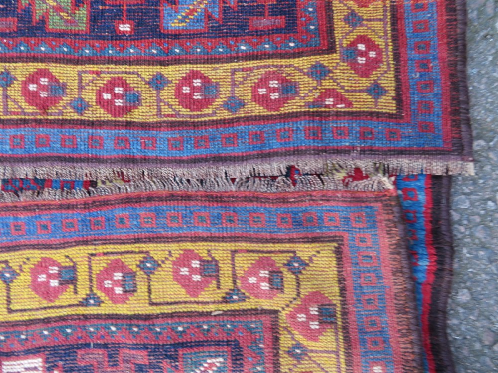 An antique hand-knotted Kurdish Kelleh long rug featuring a navy blue central field filled with repeating geometric motifs within multi-coloured yellow and red borders. View XIV