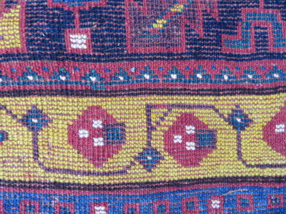 An antique hand-knotted Kurdish Kelleh long rug featuring a navy blue central field filled with repeating geometric motifs within multi-coloured yellow and red borders. View XVI