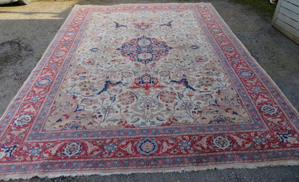 A large hand-knotted Persian Tabriz carpet featuring a central navy blue and red medallion on a cream field with floral vines and a prominent red border. View II