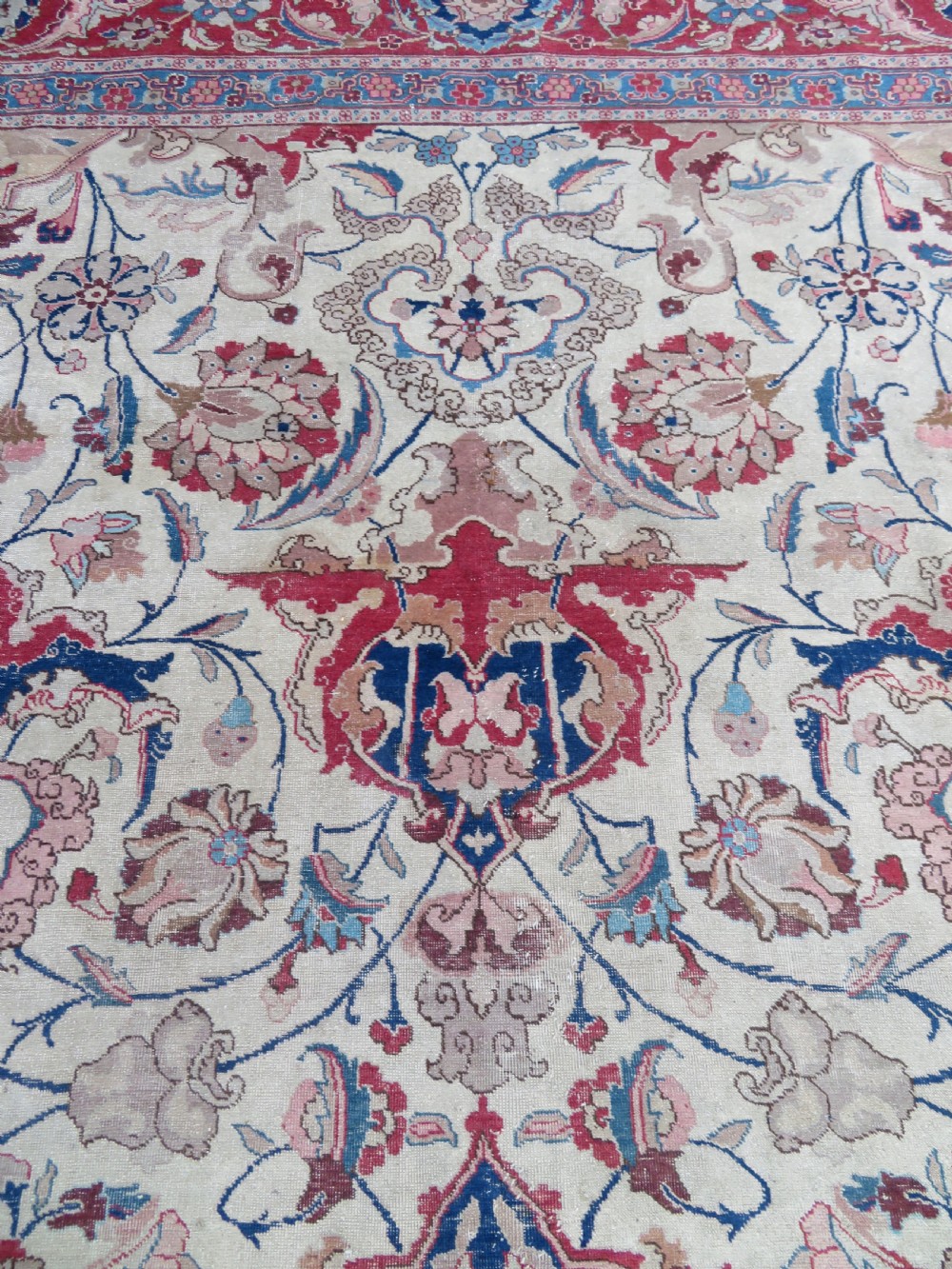 A large hand-knotted Persian Tabriz carpet featuring a central navy blue and red medallion on a cream field with floral vines and a prominent red border. View VII