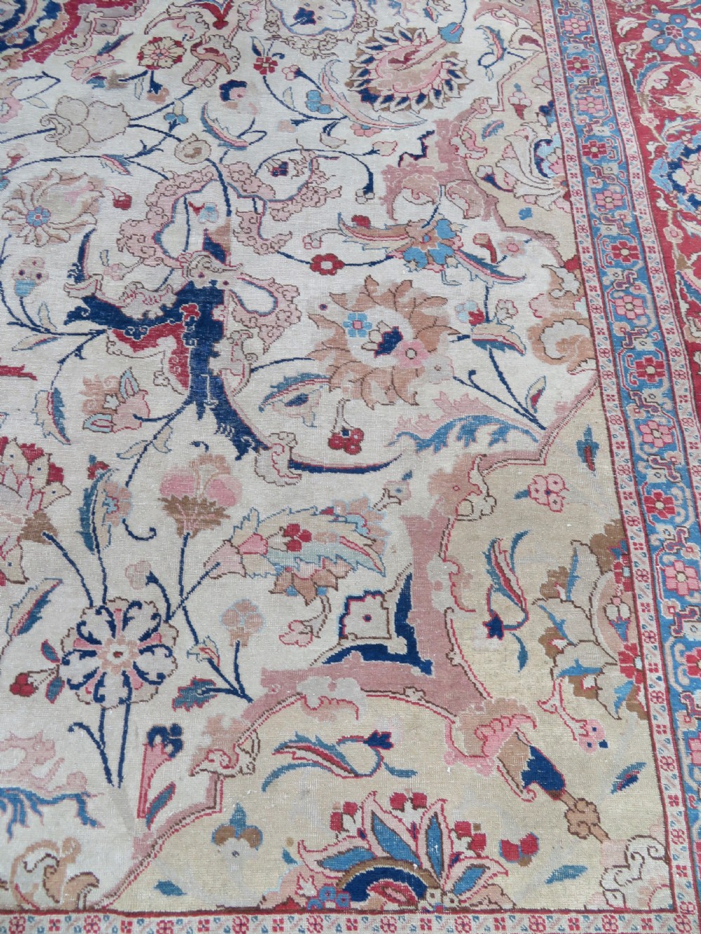 A large hand-knotted Persian Tabriz carpet featuring a central navy blue and red medallion on a cream field with floral vines and a prominent red border. View XIII