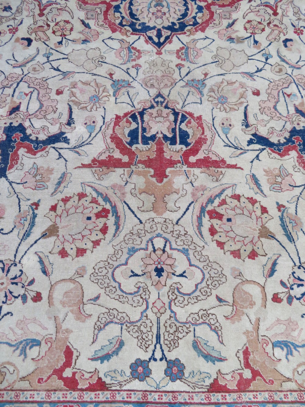 A large hand-knotted Persian Tabriz carpet featuring a central navy blue and red medallion on a cream field with floral vines and a prominent red border. View XIV