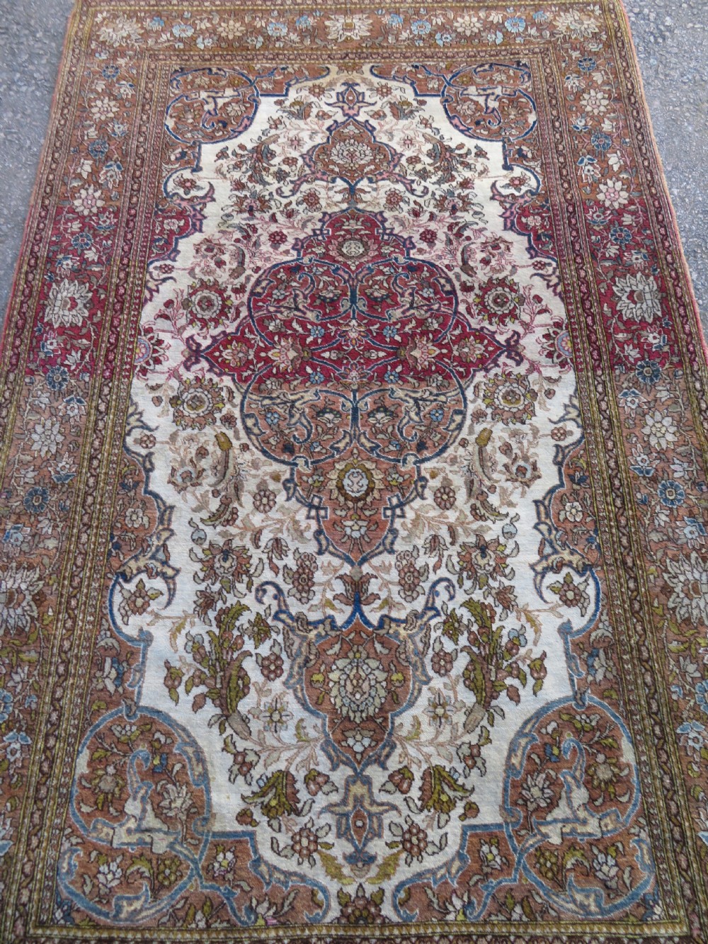 An antique hand-knotted Isfahan wool rug featuring a red central floral medallion on an ivory field surrounded by terracotta and blue floral borders. View III