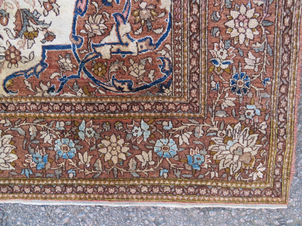 An antique hand-knotted Isfahan wool rug featuring a red central floral medallion on an ivory field surrounded by terracotta and blue floral borders. View VII