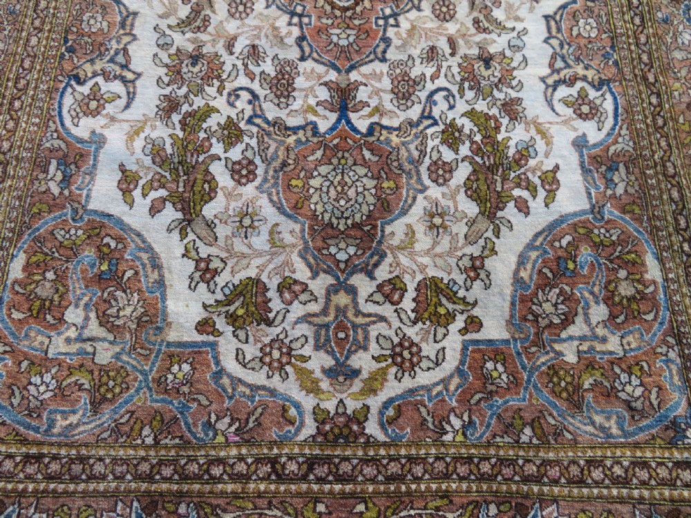 An antique hand-knotted Isfahan wool rug featuring a red central floral medallion on an ivory field surrounded by terracotta and blue floral borders. View VIII