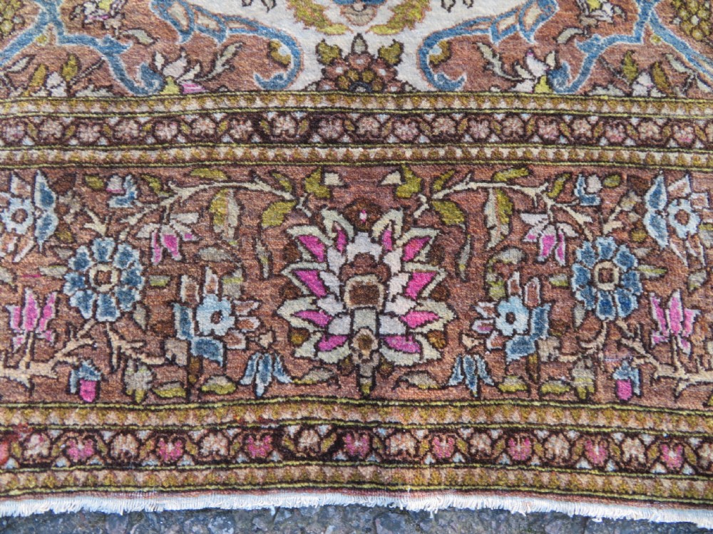 An antique hand-knotted Isfahan wool rug featuring a red central floral medallion on an ivory field surrounded by terracotta and blue floral borders. View IX