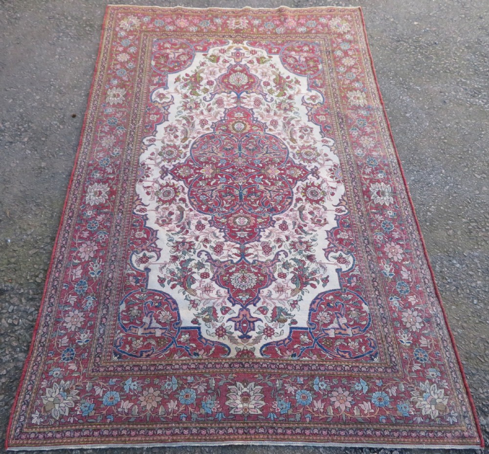 An antique hand-knotted Isfahan wool rug featuring a red central floral medallion on an ivory field surrounded by terracotta and blue floral borders. View X