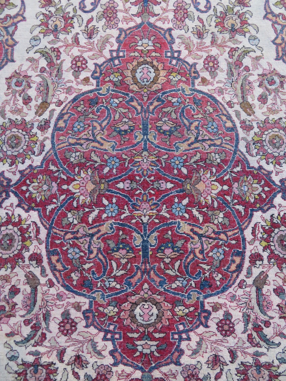 An antique hand-knotted Isfahan wool rug featuring a red central floral medallion on an ivory field surrounded by terracotta and blue floral borders. View XI